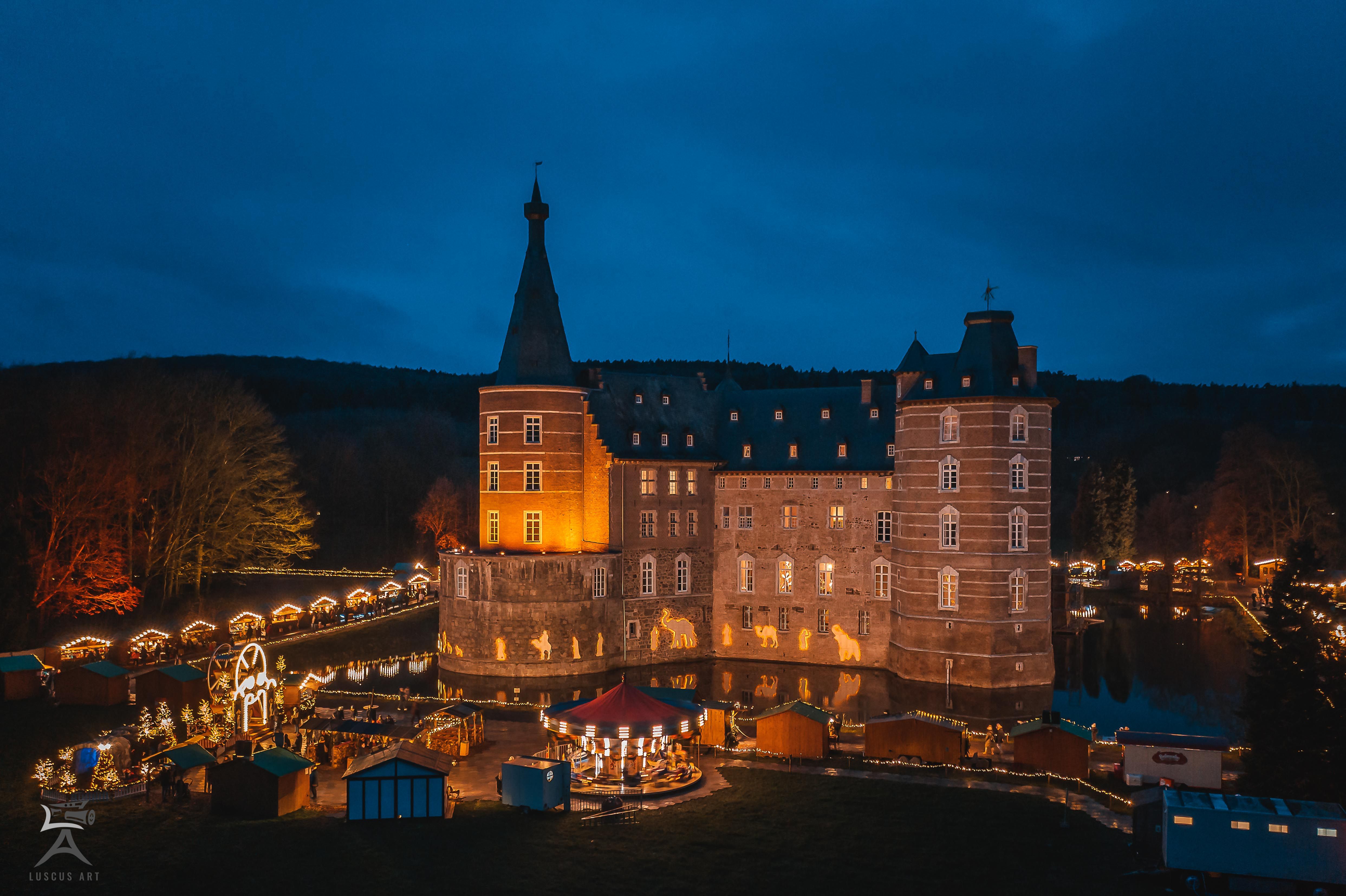 Kasteel Merode bij nacht, feestelijk verlicht met kerstmarktkraampjes op de voorgrond.