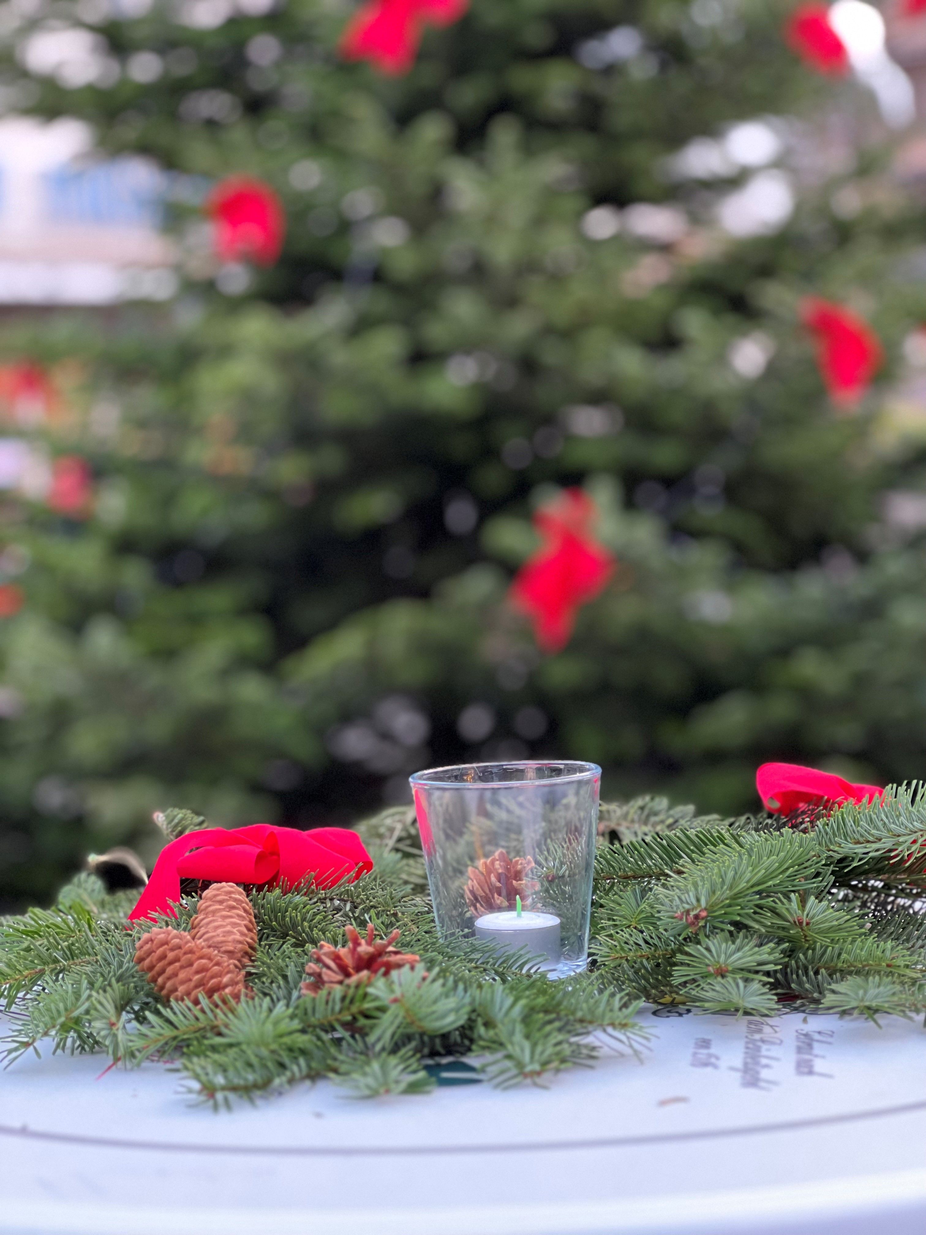 Adventskrans met rode strikken en dennenappels op een tafel bij de Herdecker Weihnachtszauber.