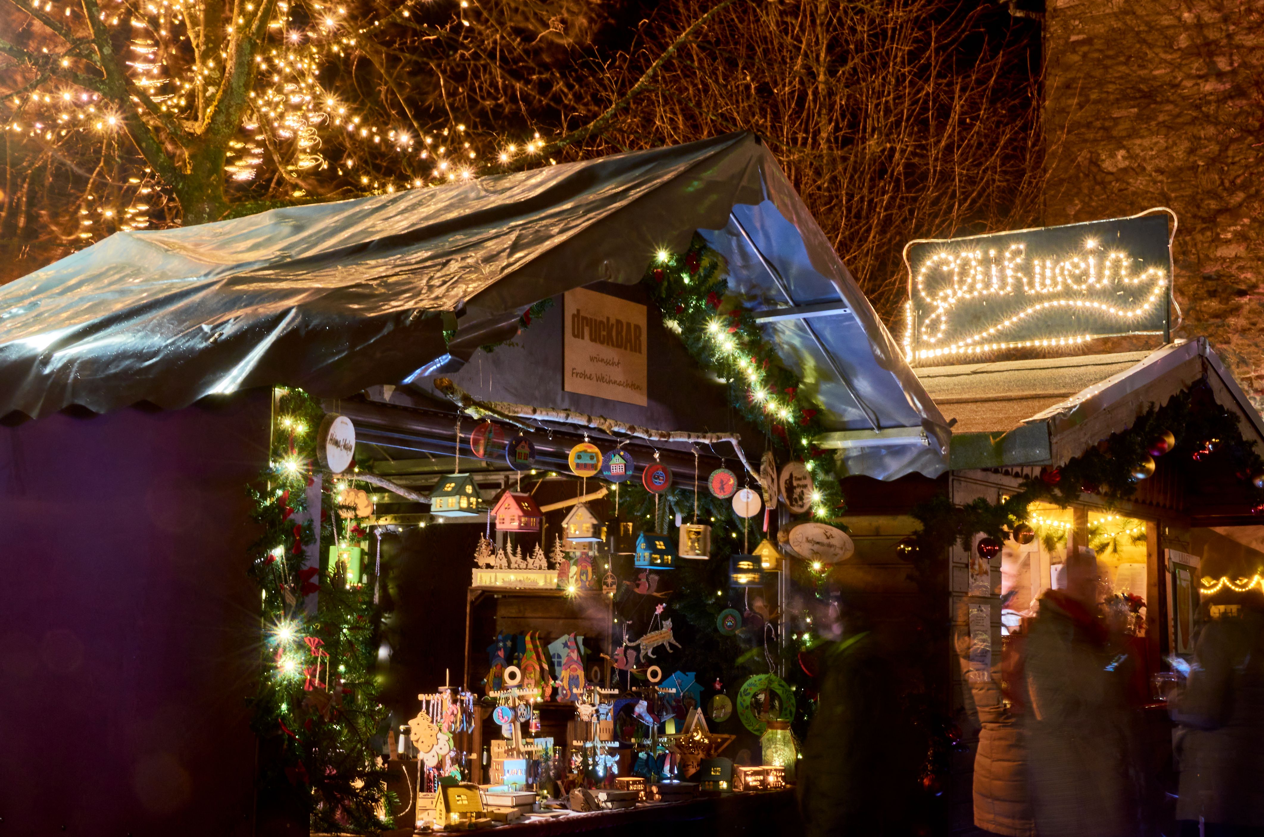 Een feestelijk verlichte kraam op de kerstmarkt in Kürten, versierd met lichtjes en kerstversieringen.