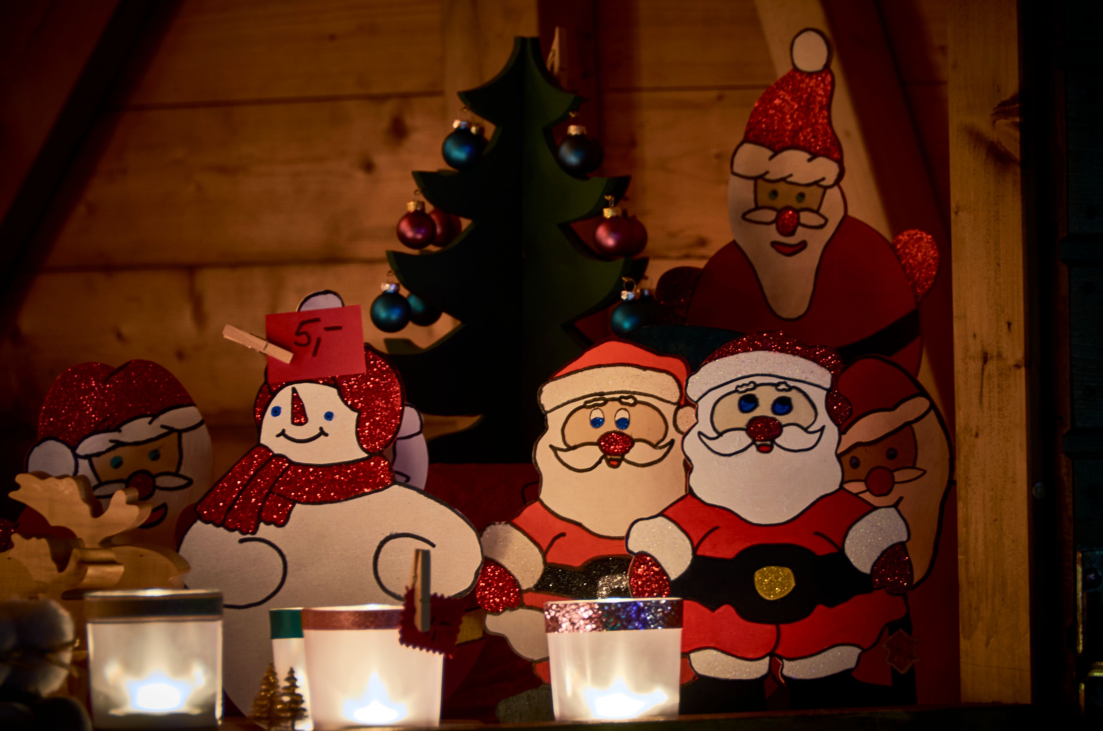 Houten figuren van kerstmannen en een sneeuwpop op een kerstmarktkraam.