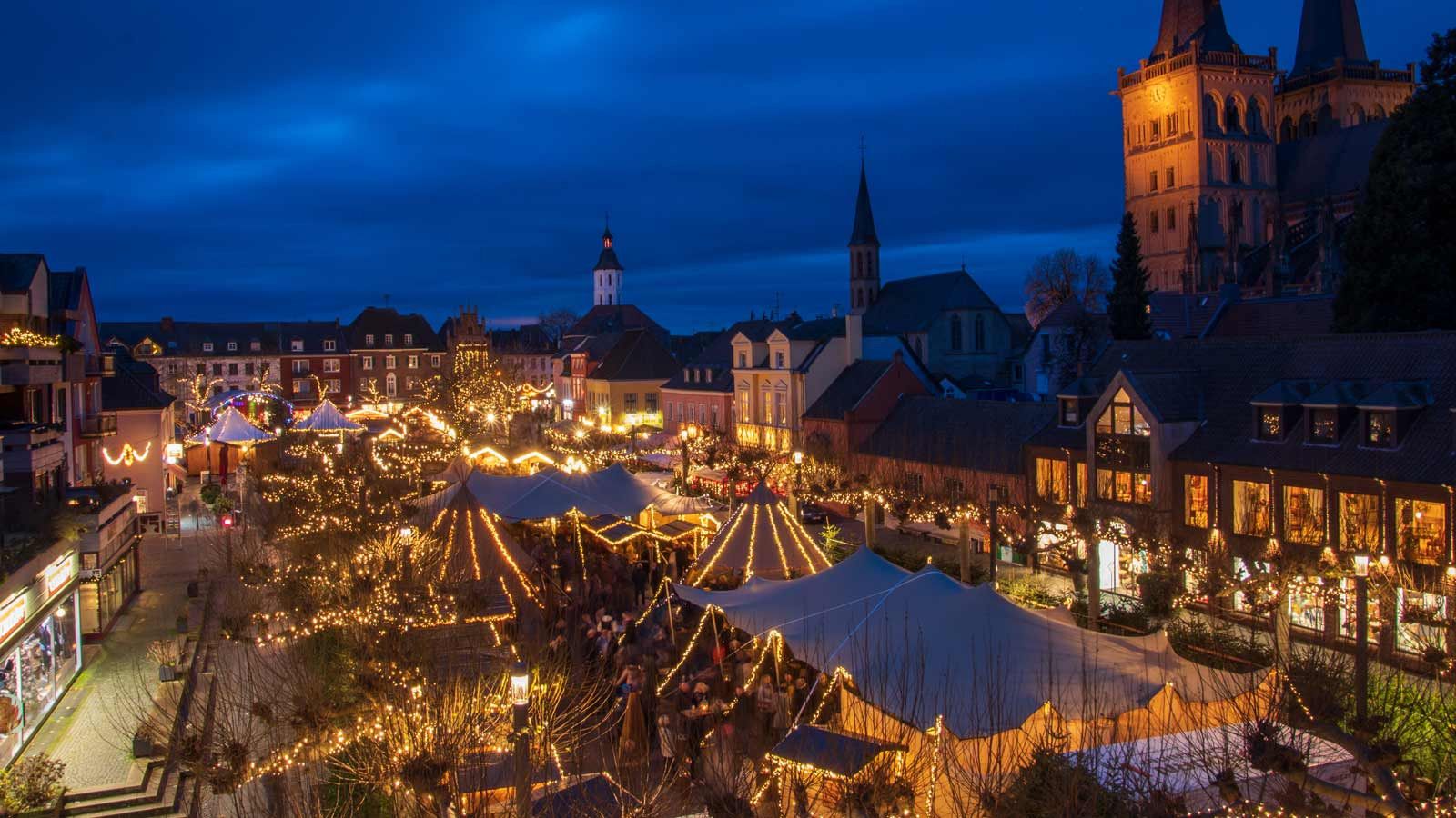 De kerstmarkt in Xanten schittert 's avonds in een feestelijke gloed van lichtjes met talloze kraampjes en tenten.