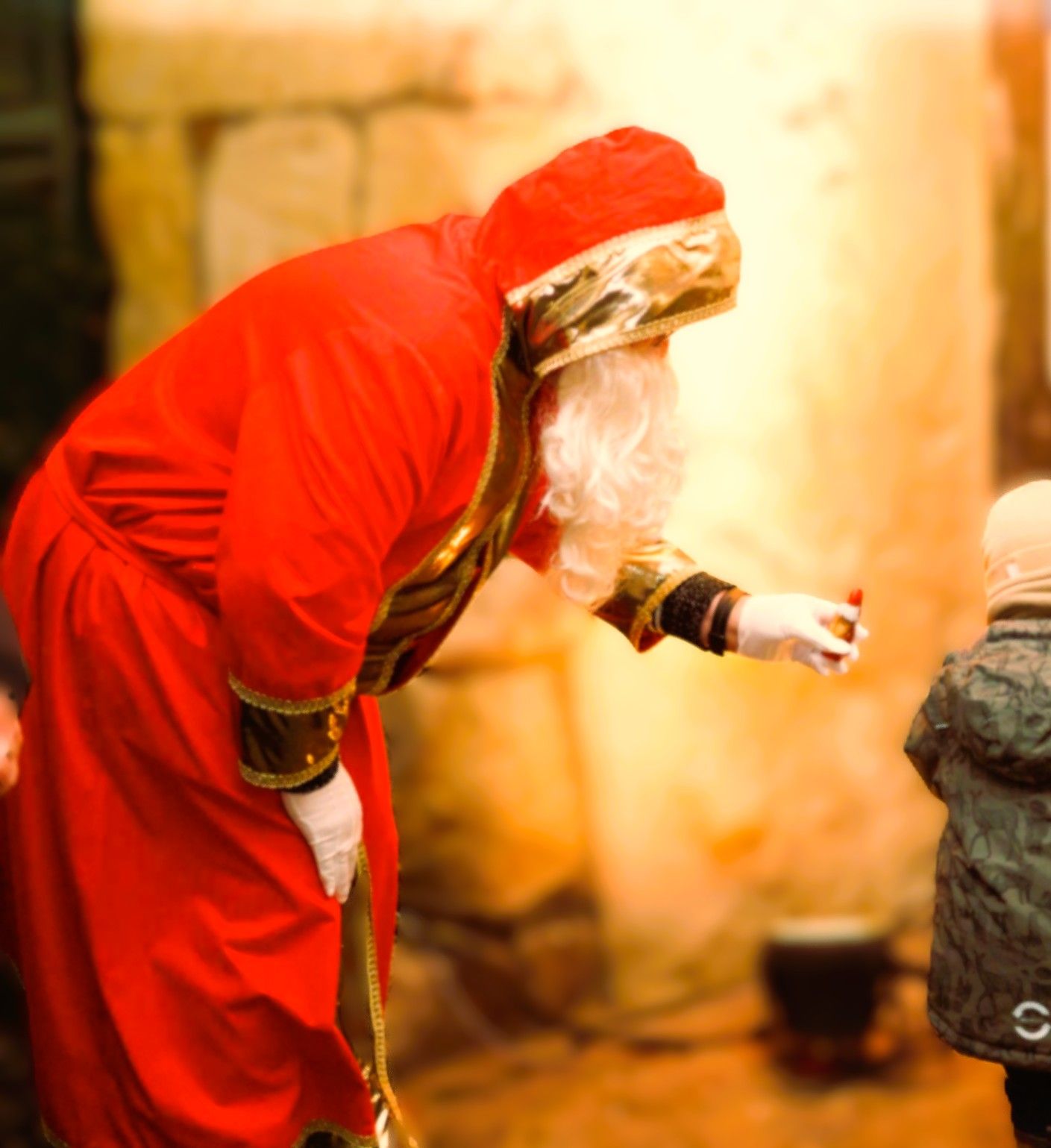 Sinterklaas in een rood gewaad overhandigt een cadeau aan een kind op de Sinterklaasmarkt in Tecklenburg. 