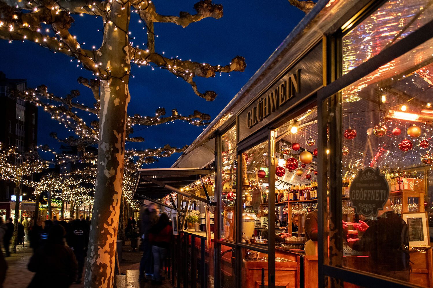 Bomen en kraampjes zijn versierd met lichtjes op de kerstpromenade in Düsseldorf.