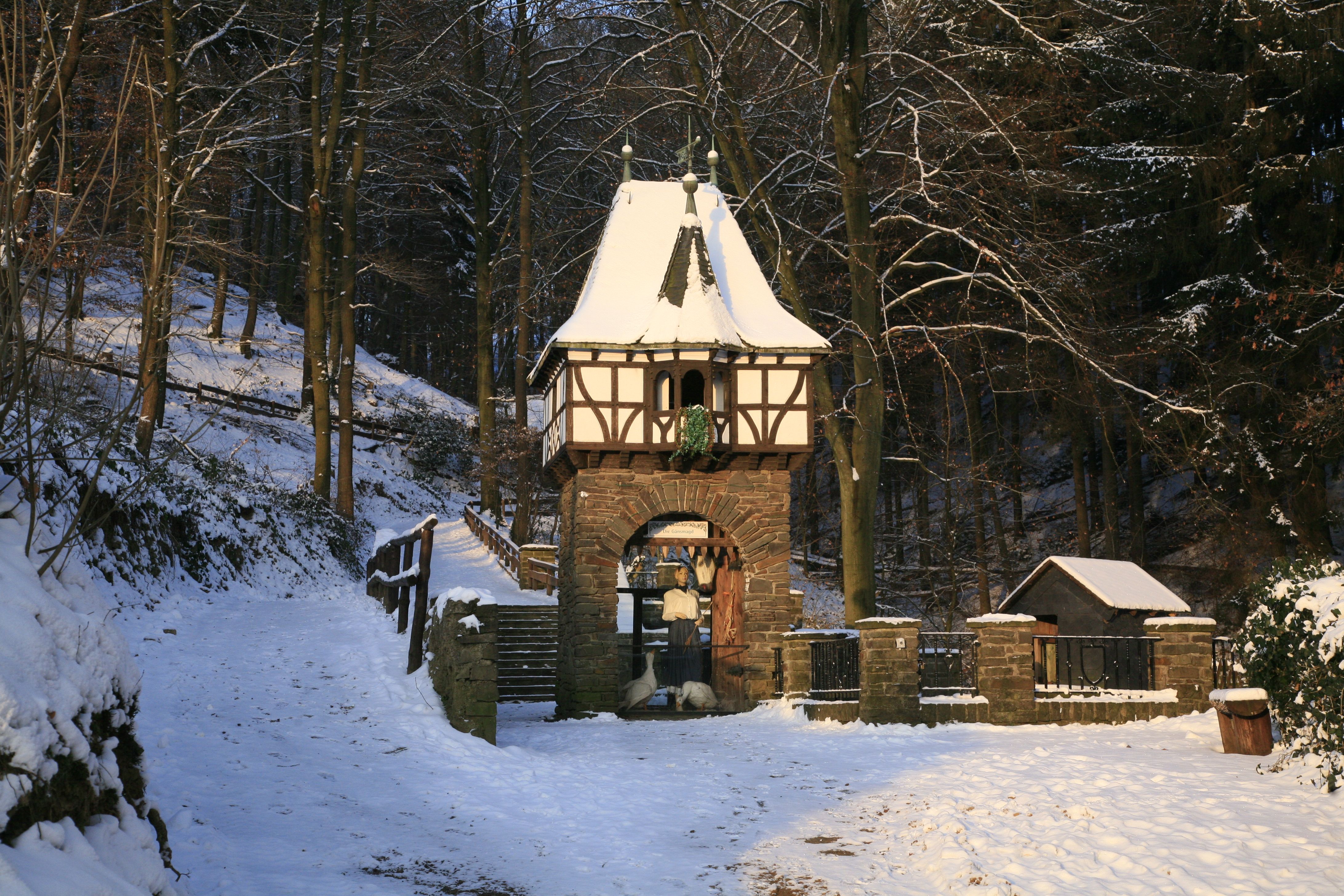 Een met sneeuw bedekt poortgebouw in een sprookjesbos.