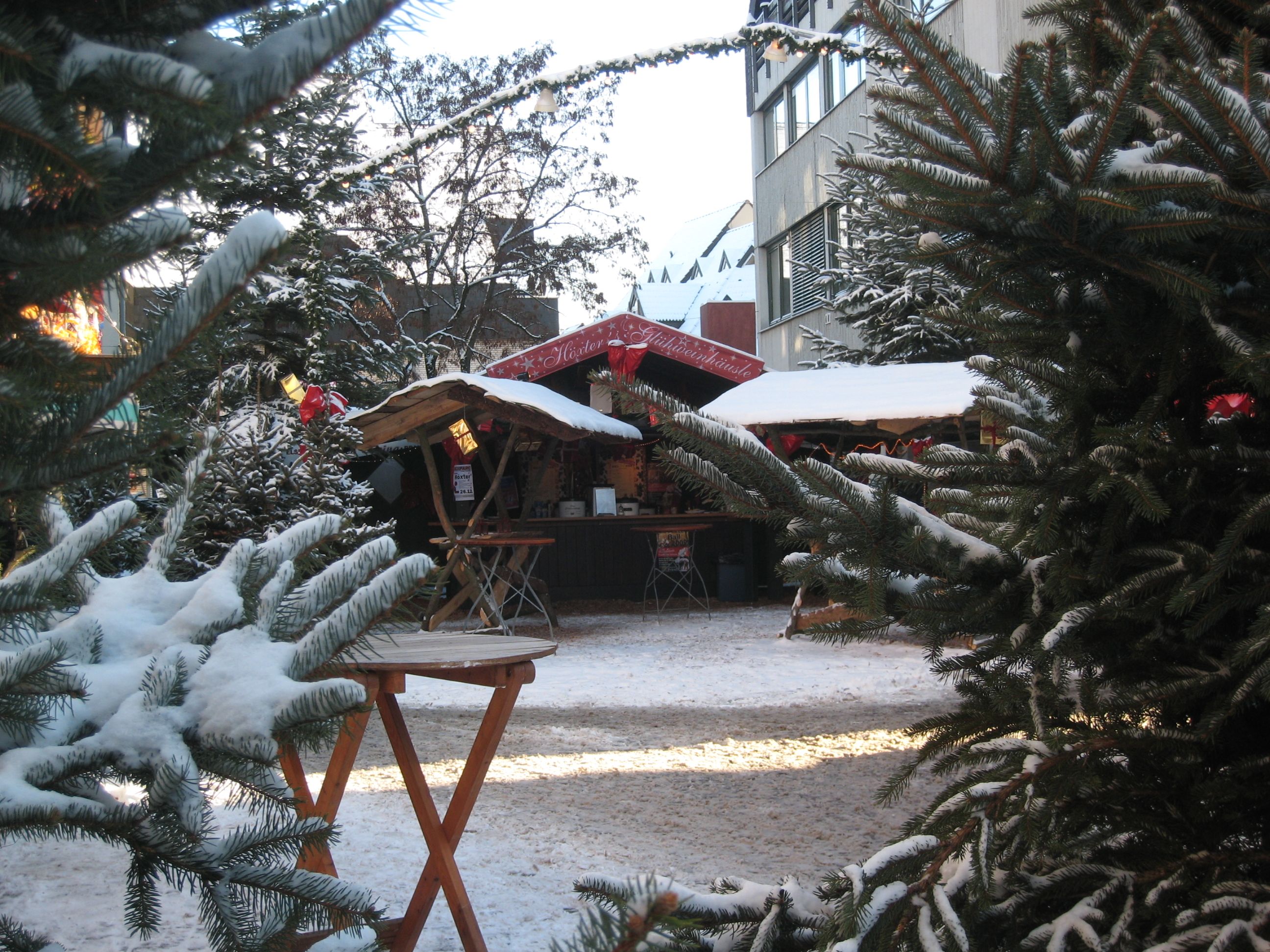 Besneeuwde kerstmarkt in Höxter met dennenbomen en houten hutten.