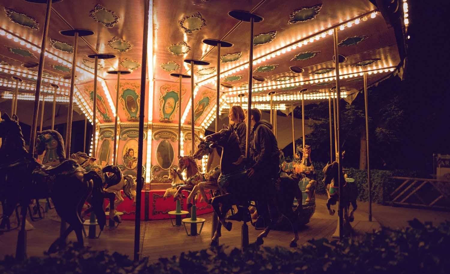 Een paardencarrousel versierd met gloeiende lichtjes en mensen die op paarden zitten.