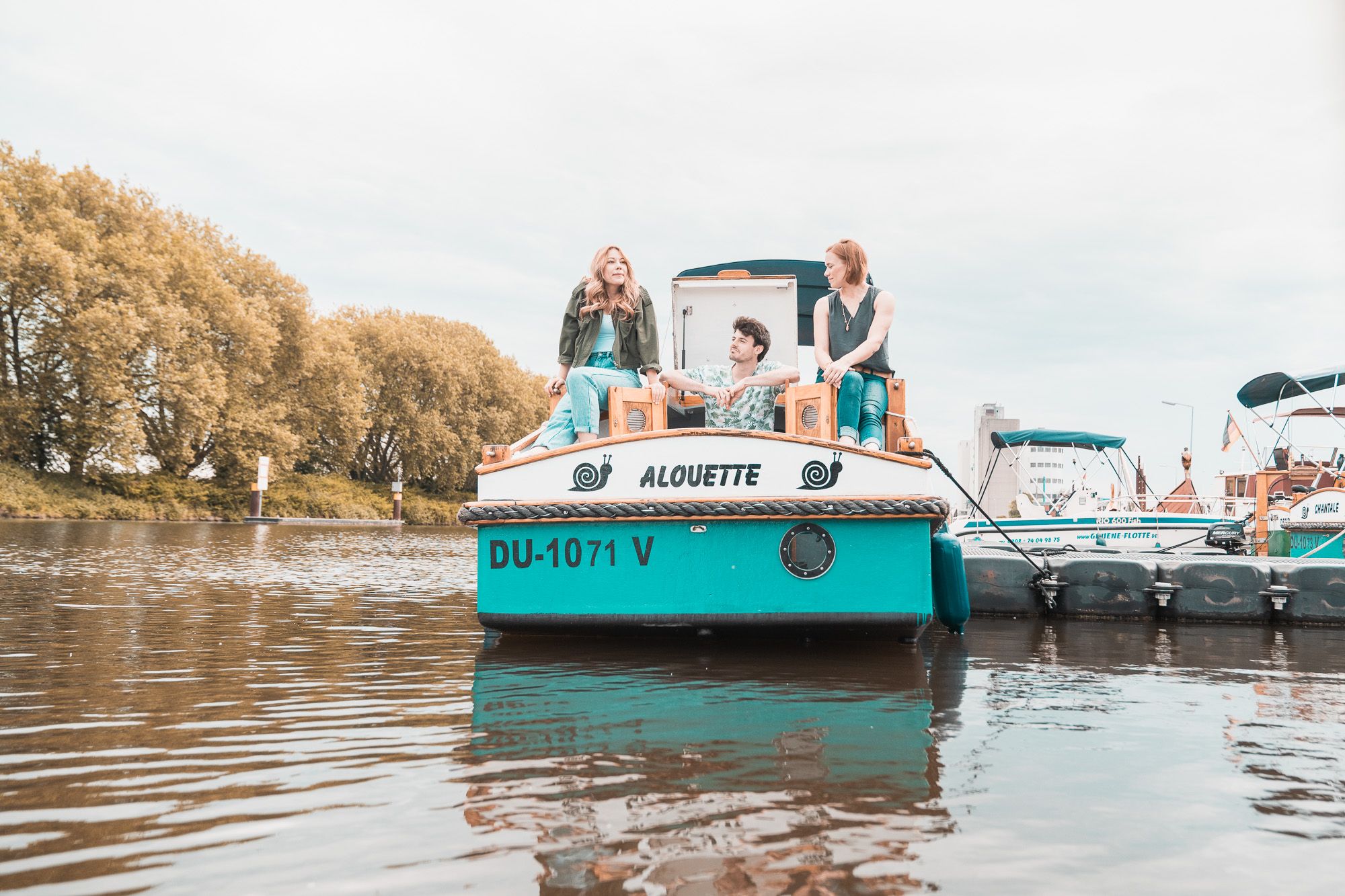 Zwei Frauen und ein Mann sitzen auf einem Hausboot 