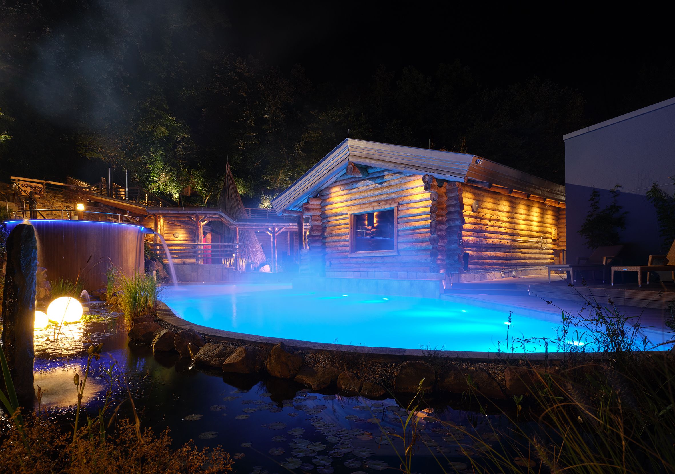 De Carolus Therme bij nacht, verlicht met blauw licht.