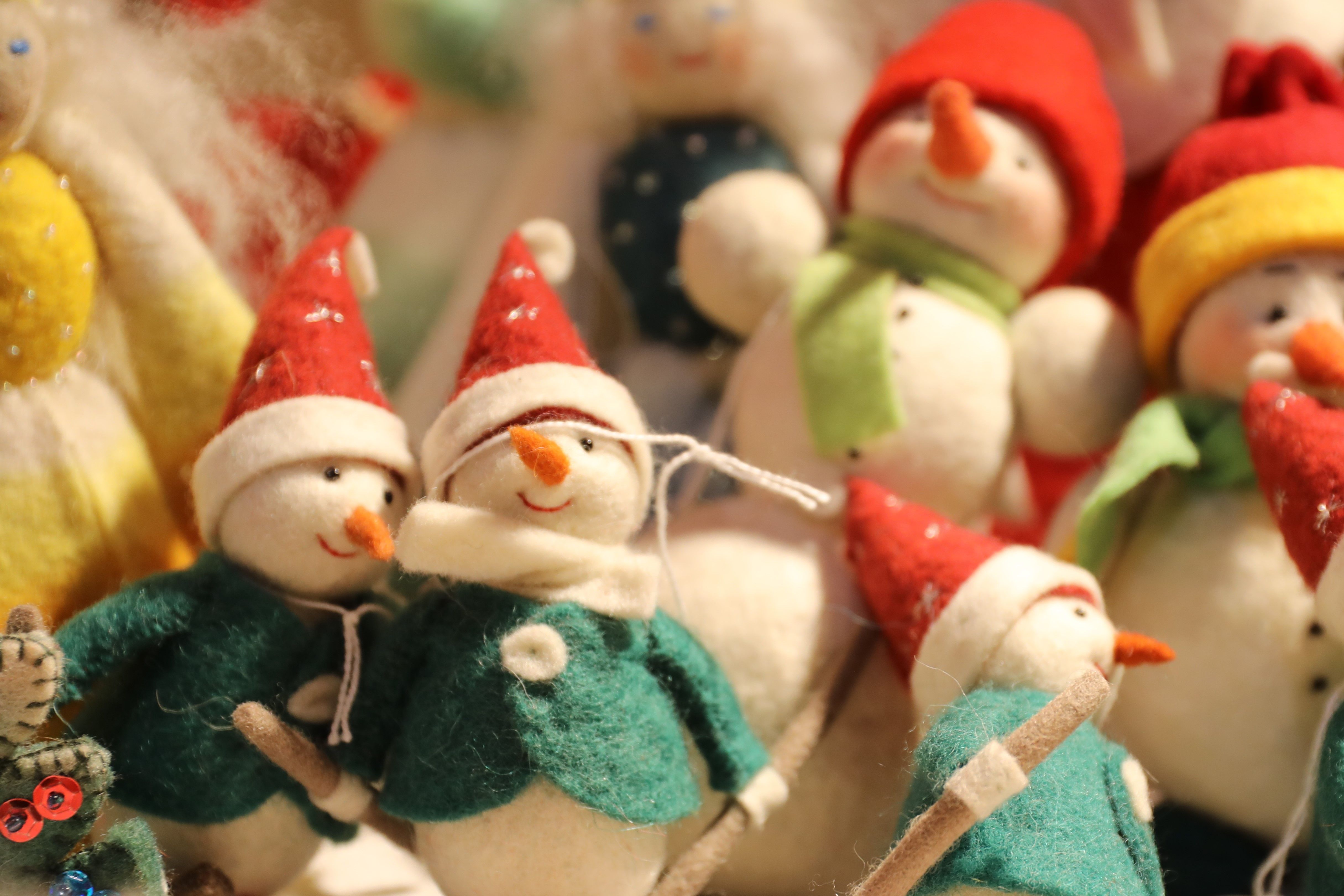 Vilten sneeuwpoppen met rode mutsen en groene sjaals, decoratief gepresenteerd op de kerstmarkt op kasteel Eulenbroich.