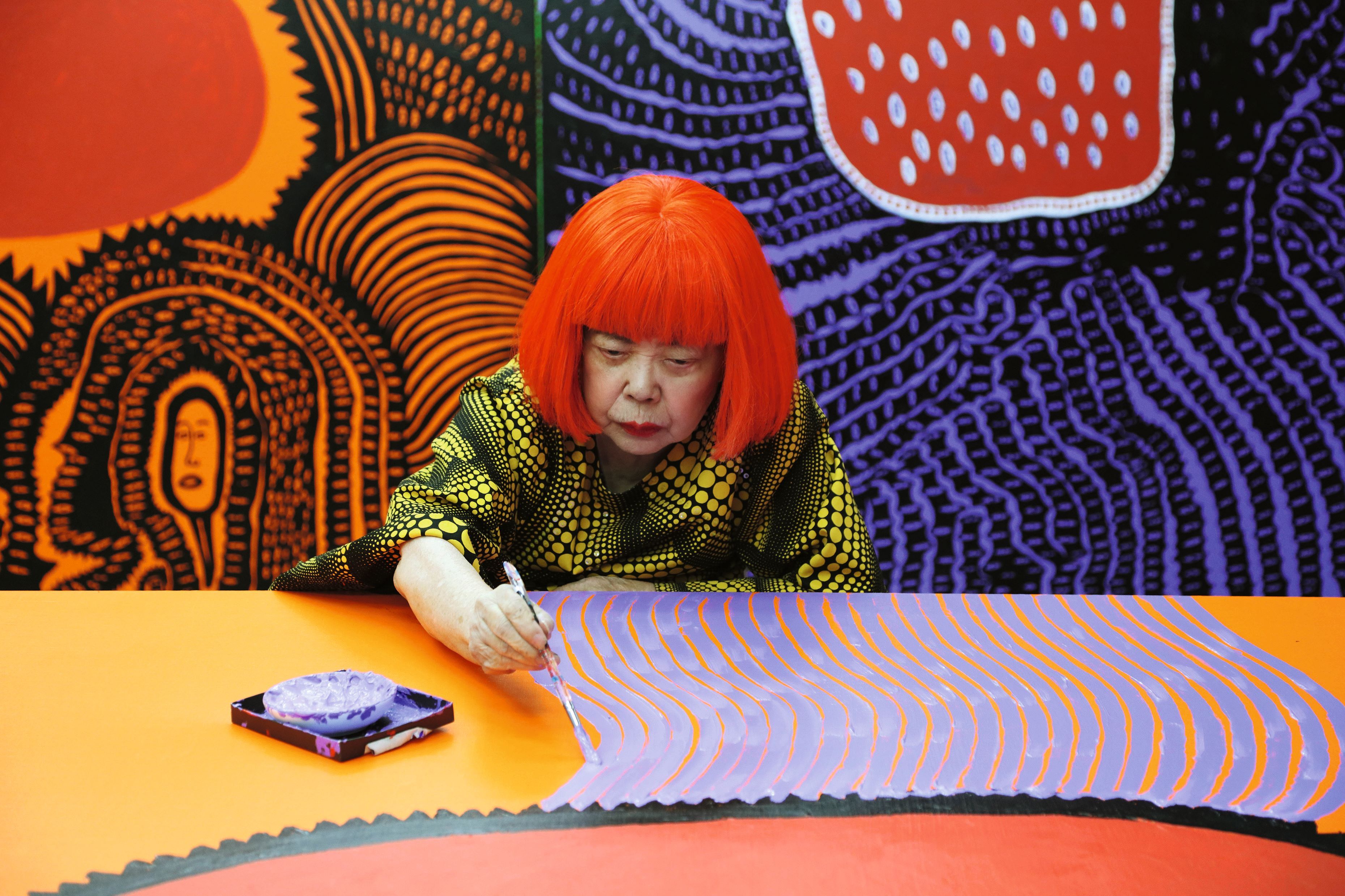 Künstlerin mit leuchtend roten Haaren bei der Arbeit Yayoi Kusama bei der Arbeit an "My Eternal Soul"