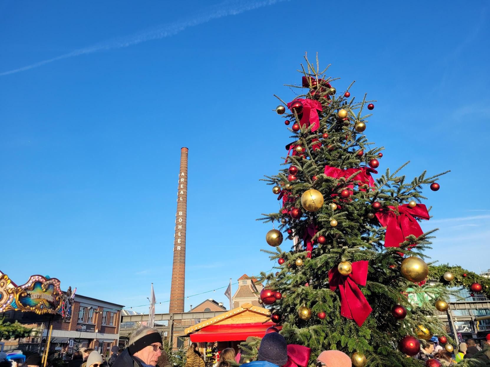 Een grote feestelijk versierde kerstboom staat in het midden van de  Weihnachtszauber Areal Böhler in Düsseldorf.