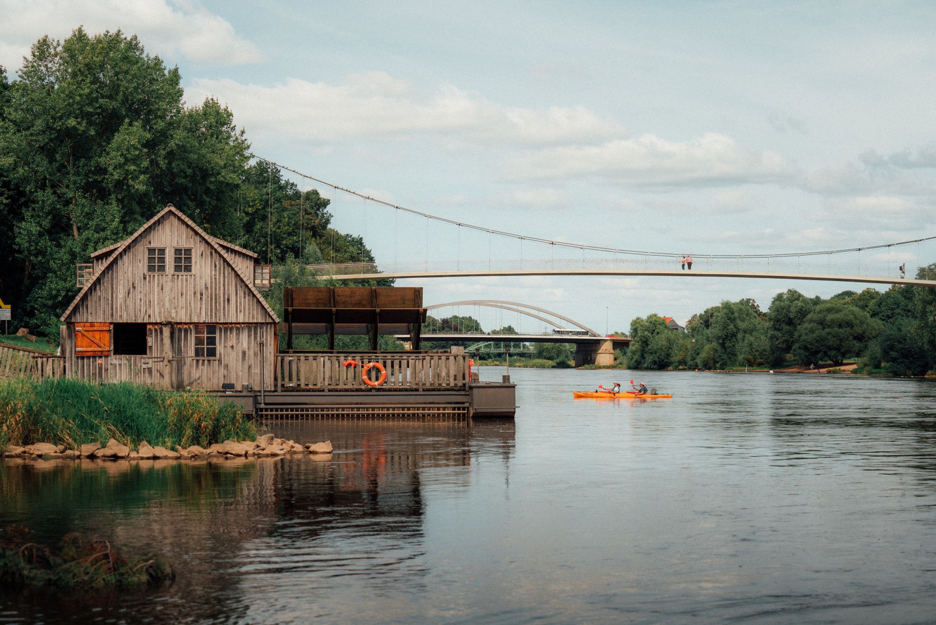 Historische Mühle an einem Fluss, auf dem ein Kajakfahrer fährt