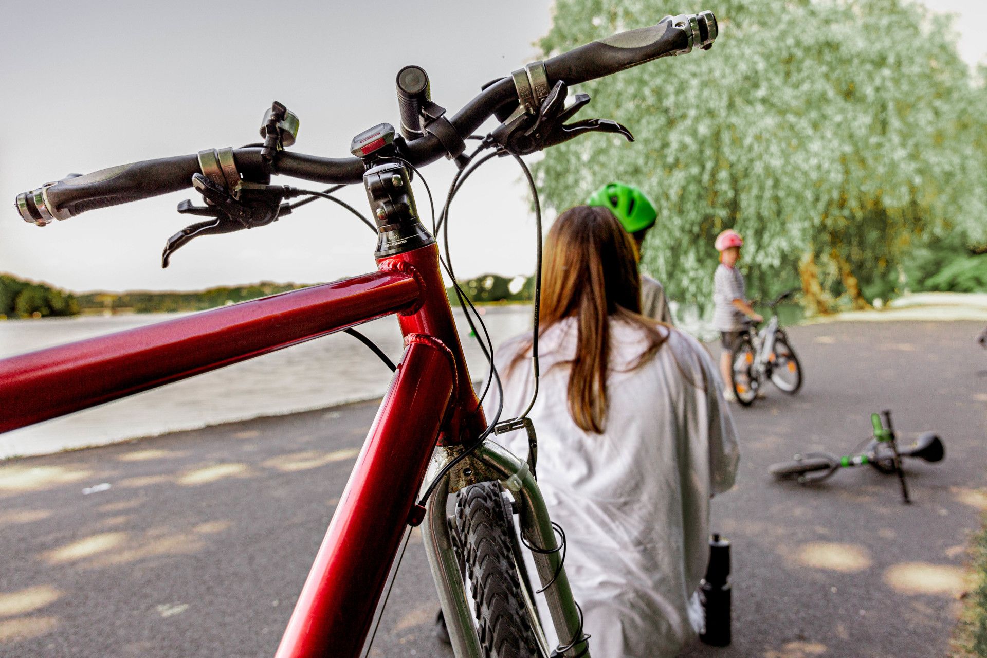Op de voorgrond staat een rode fiets, terwijl op de achtergrond een gezin samen tijd doorbrengt