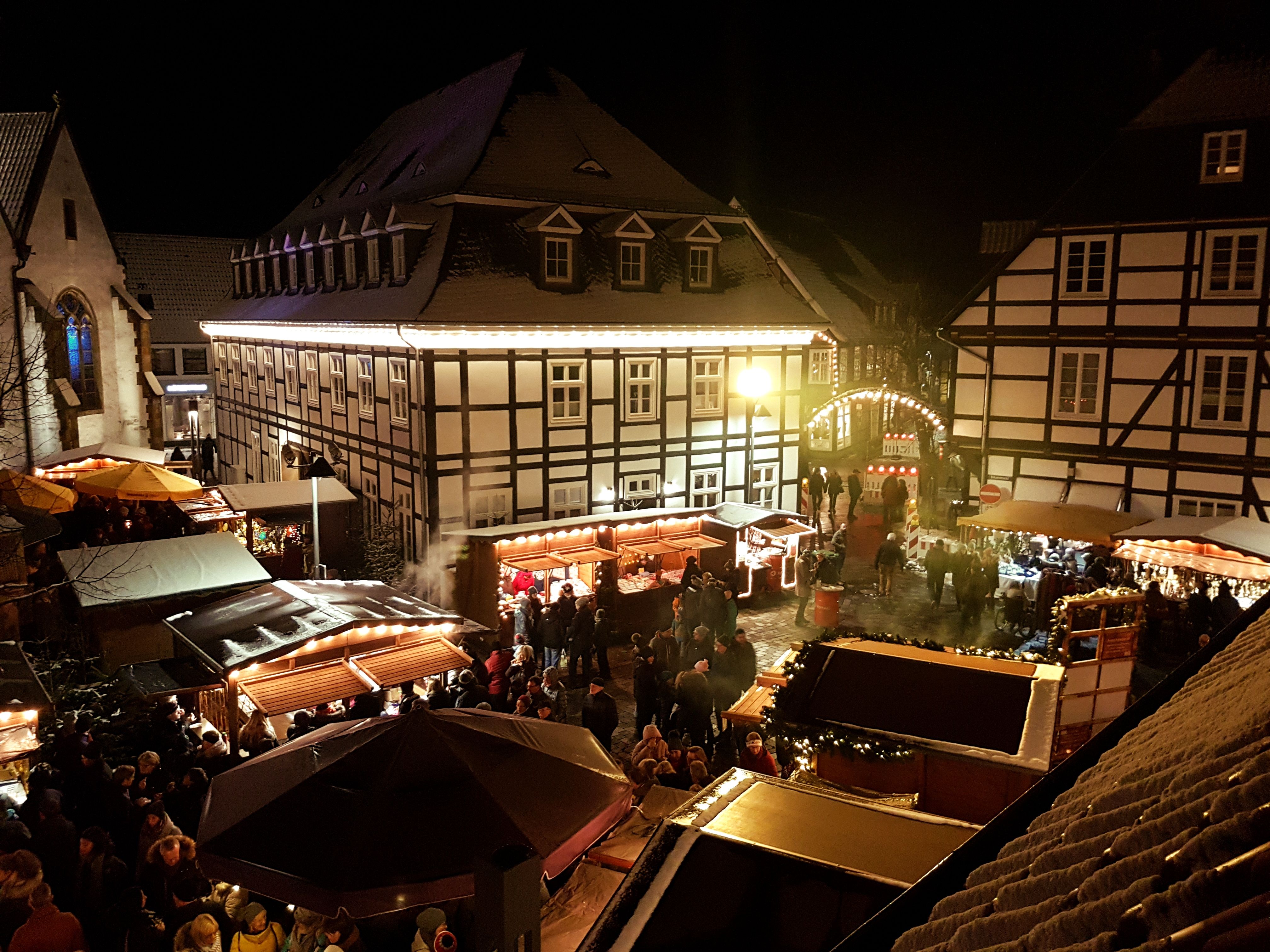 Levendige adventsmarkt in Rietberg bij nacht, omringd door verlichte vakwerkhuizen en feestelijk versierde kraampjes.