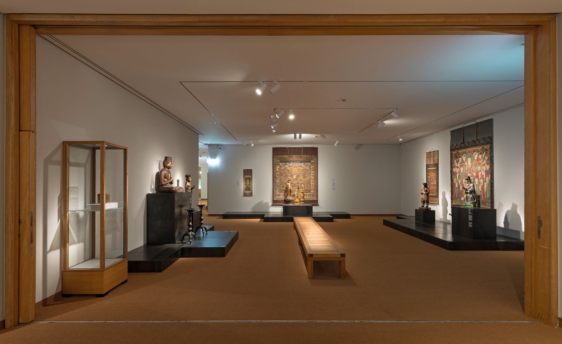 Een blik in een tentoonstellingszaal van het Museum voor Oost-Aziatische Kunst met boeddhistische kunstwerken uit Oost-Azië, waaronder beeldhouwwerken, rituele voorwerpen en hangrollen
